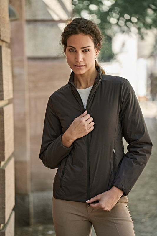 Woman wearing the Tee Jays Ladies PureLite Jacket in Black, zipping it up outdoors