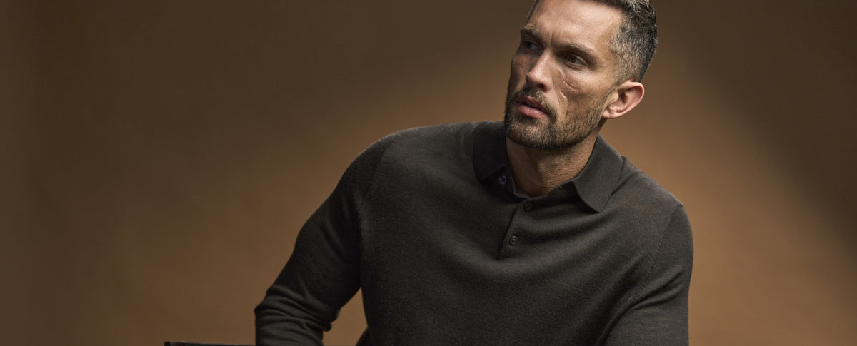 Man wearing the Tee Jays Men’s Knit Polo Shirt in Mocha, against a warm brown backdrop
