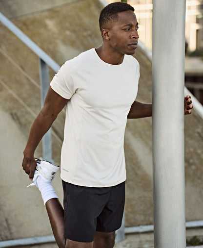 Man wearing the Tee Jays Men’s CoolDry T-Shirt, stretching by a lamp post