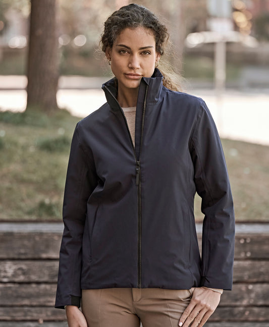 Woman wearing the Tee Jays Ladies All Weather Jacket in Deep Navy, standing in a park