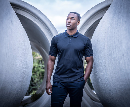 Man wearing the Regatta Recycle.Me Unisex Pique Polo Shirt, standing among large concrete pipes