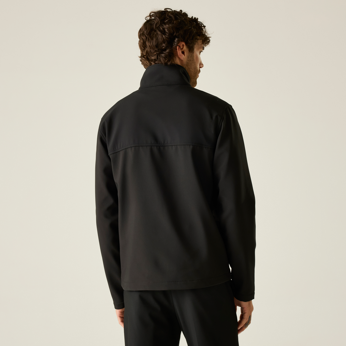Model wearing the Regatta Recycle.Me Unisex Softshell Jacket in Black, back view