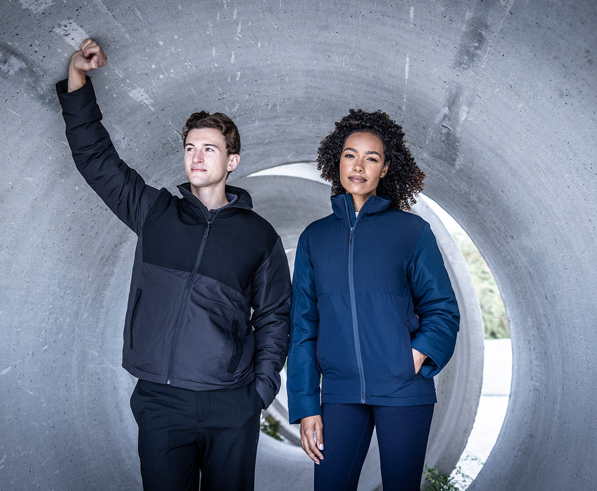 Man and woman wearing the Regatta Recycle.Me Thermal Jacket, standing in a concrete pipe