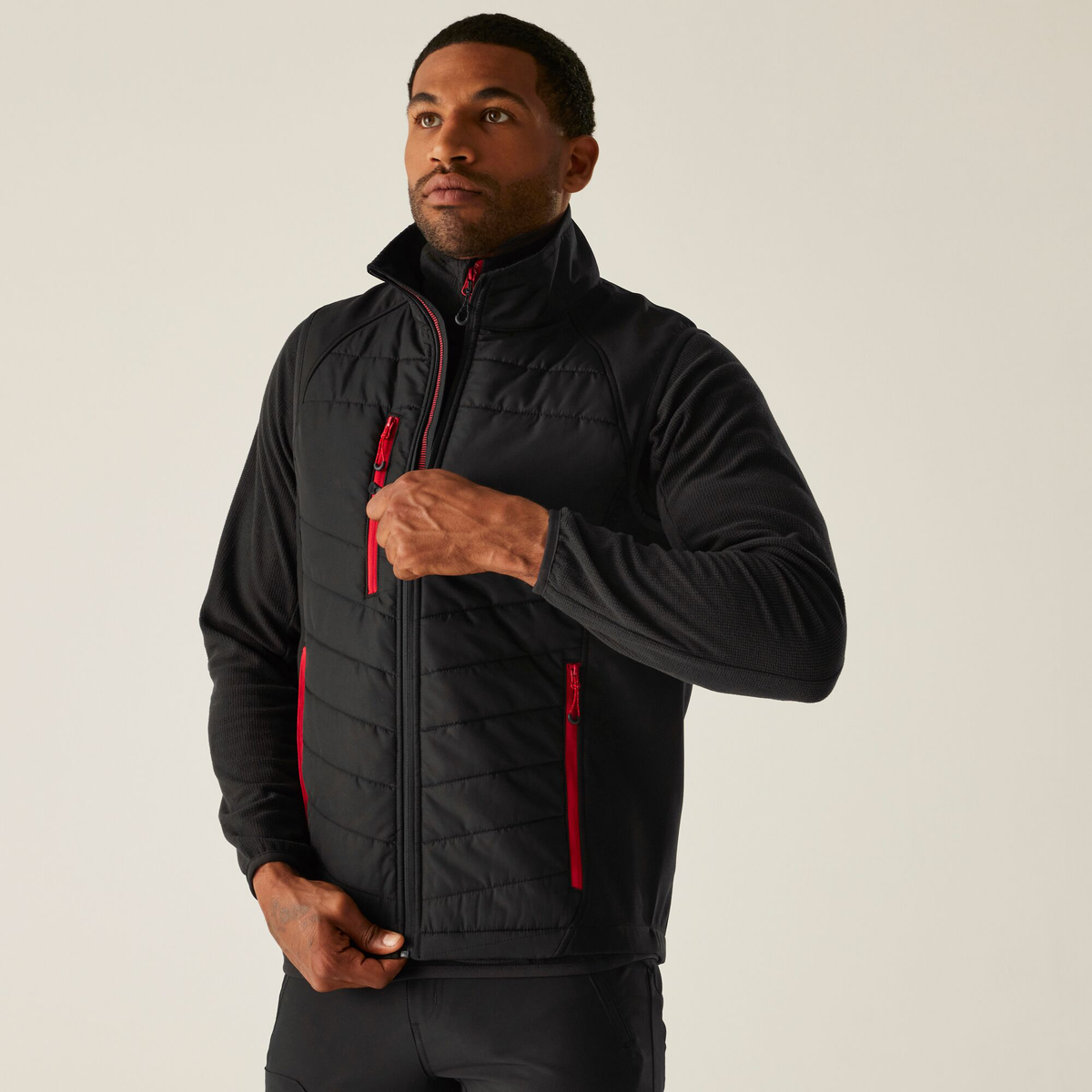 Model wearing the Regatta Pro Men’s Universal Bodywarmer in Black and Classic Red, front view, zipping it up