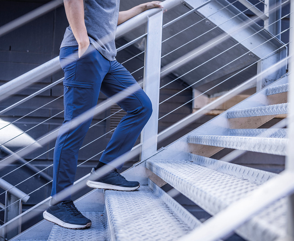 Man wearing the Regatta Pro Men’s Action Stretch Trousers in Navy, climbing metal steps