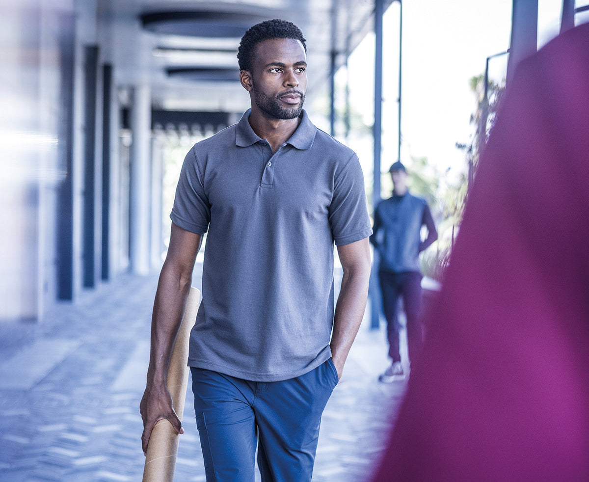 Man wearing the Regatta Pro Men’s 50/50 Pique Polo Shirt, walking under a colonnade