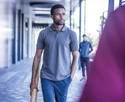 Man wearing the Regatta Pro Men’s 50/50 Pique Polo Shirt, walking under a colonnade