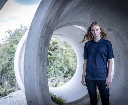 Woman wearing the Regatta Recycle.Me Unisex Pique Polo Shirt in Navy, standing in a concrete pipe