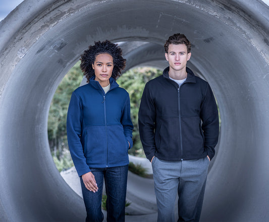 Woman and man wearing the Regatta Recycle.Me Unisex Fleece Jacket, standing in a concrete pipe