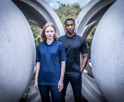 Woman and man wearing the Regatta Recycle.Me Unisex Pique Polo Shirt, standing among large concrete pipes
