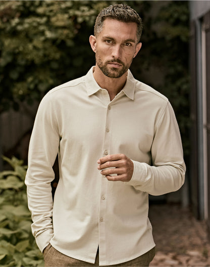 Man wearing the Tee Jays Men’s Luxury Stretch Shirt in Cement, standing in a garden