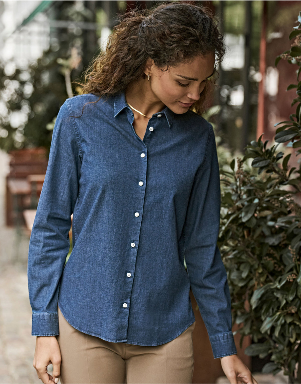 Woman wearing the Tee Jays Ladies Denim Shirt in Blue Denim, standing in a garden