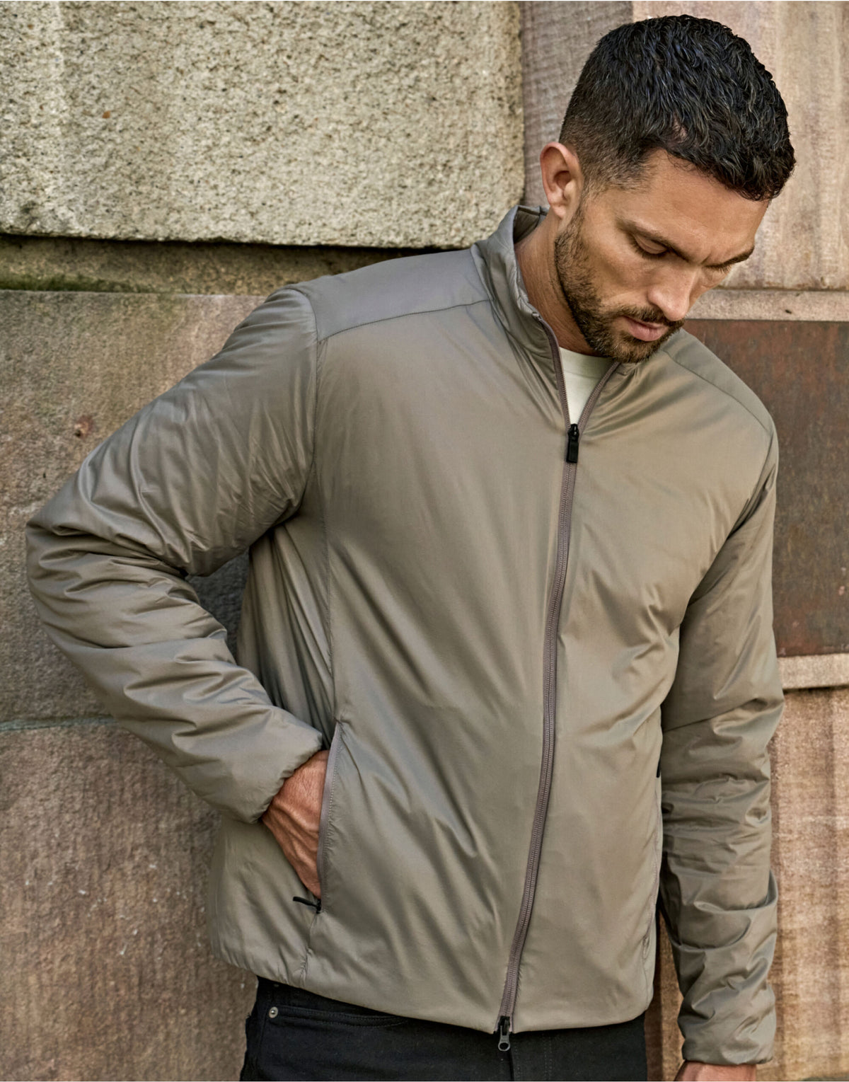 Man wearing the Tee Jays Men’s PureLite Jacket in Driftwood, hand in pocket, looking down