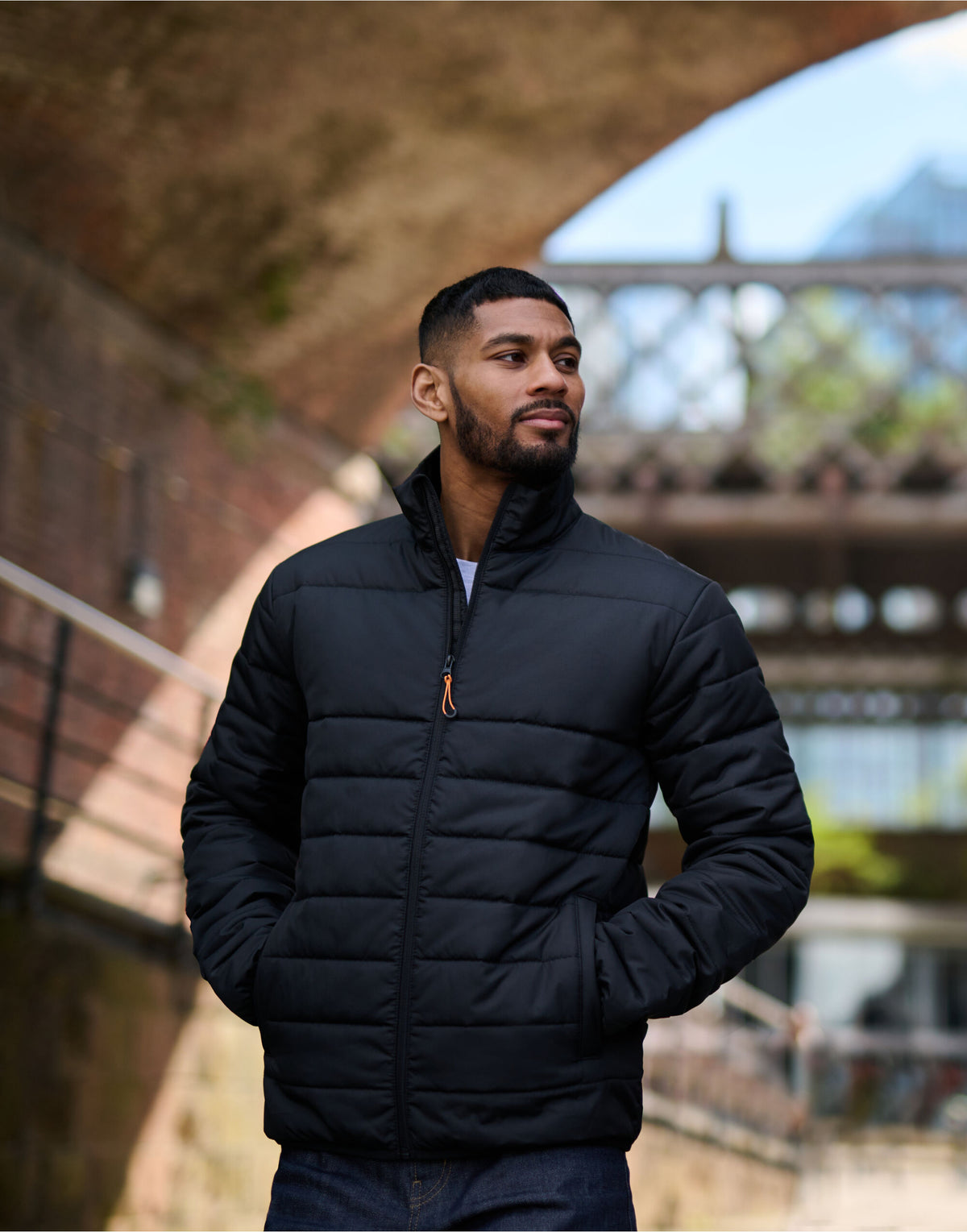 Man wearing the Regatta Essential Men's Thermal Jacket, beneath a brick railway arch