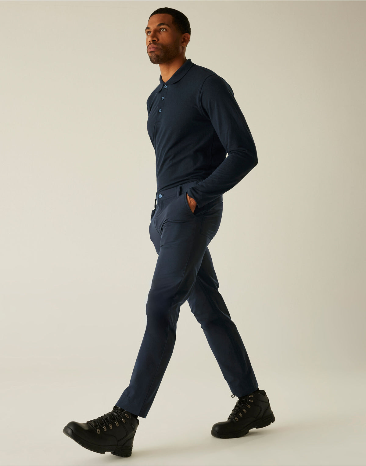 Model wearing the Regatta Pro Men’s Action Stretch Trousers Regular Fit in Navy, side view, walking