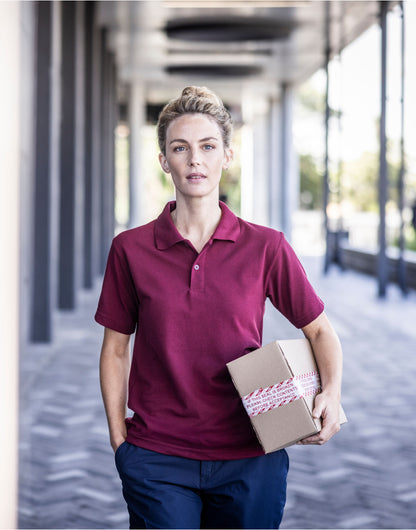 Woman wearing the Regatta Pro Men’s 50/50 Pique Polo Shirt in Burgundy, holding a parcel under a colonnade