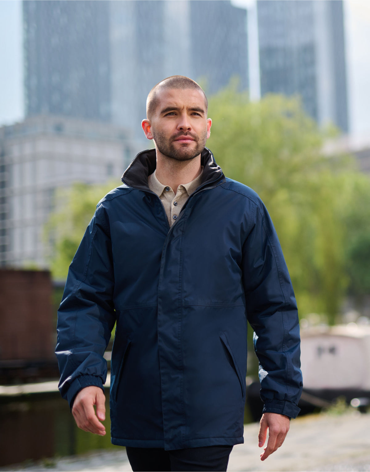 Man wearing the Regatta Dover Men's Parka in Navy, walking beside a canal in the city