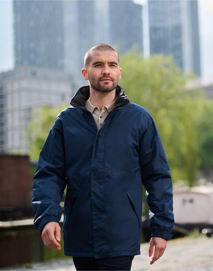 Man wearing the Regatta Dover Men's Parka in Navy, walking beside a canal in the city