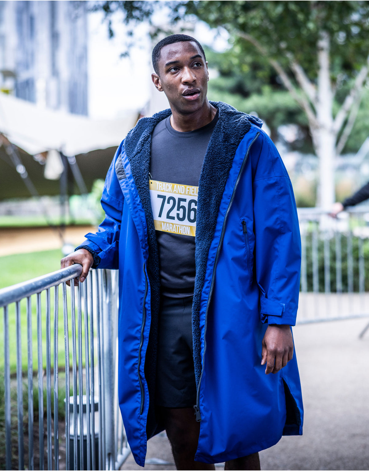 Runner with a race number wearing the Regatta Pro Changing Dryrobe Jacket in New Royal and Navy, leaning on a railing